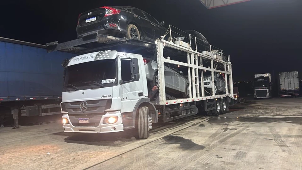 Caminhão-cegonha Mercedes carregado durante uma operação noturna.